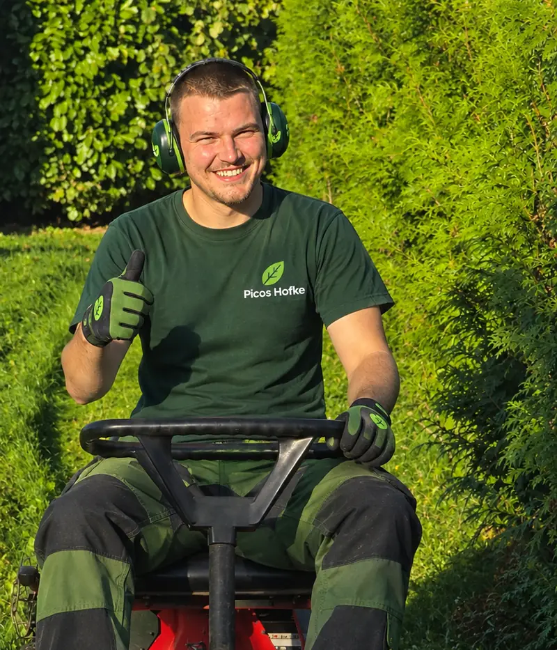 Mauro, tuinman uit Vremde, op zijn rode zitmaaier met duim omhoog