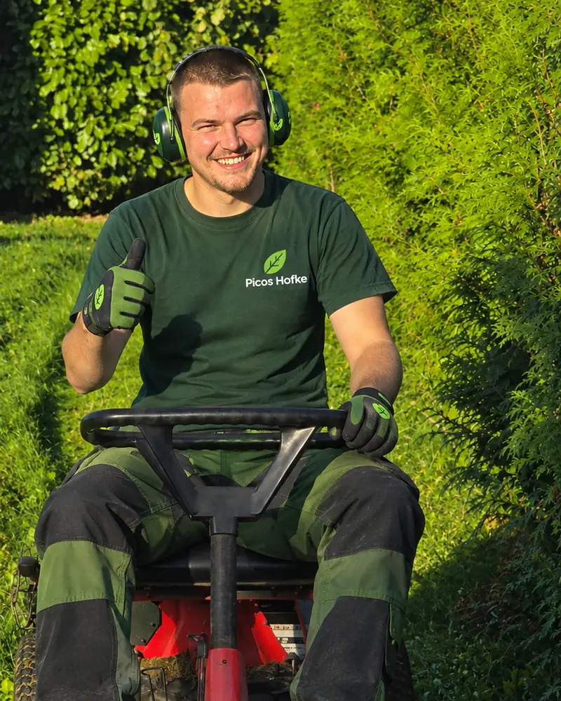 Mauro, tuinman uit Vremde, aan het gras maaien op zijn rode zitmaaier